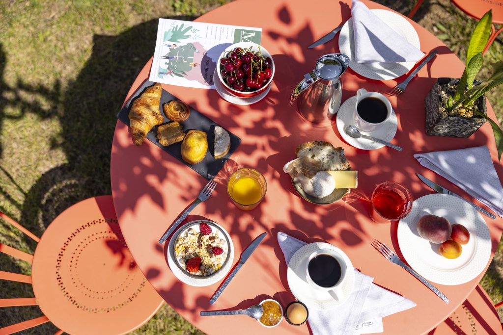 table de petit-déjeuner en extérieur aux Murets, très garni, fruits de saison, produits locaux et maison, à Chandolas
